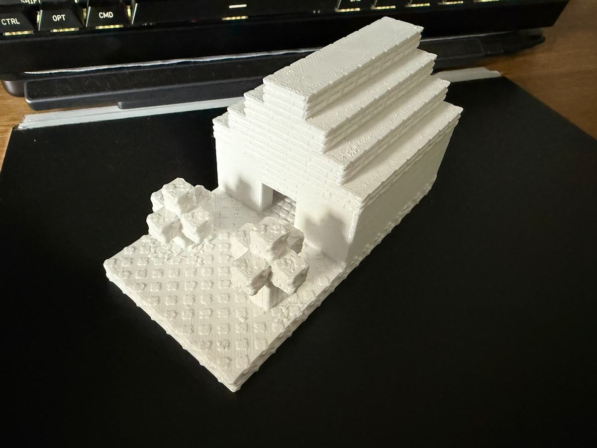 From screen to desk: the same house shown in the header, 3D printed in white, with its stepped roof, doorway and garden details.